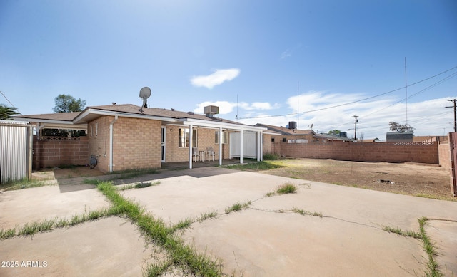 rear view of house featuring a patio area, brick siding, and a fenced backyard