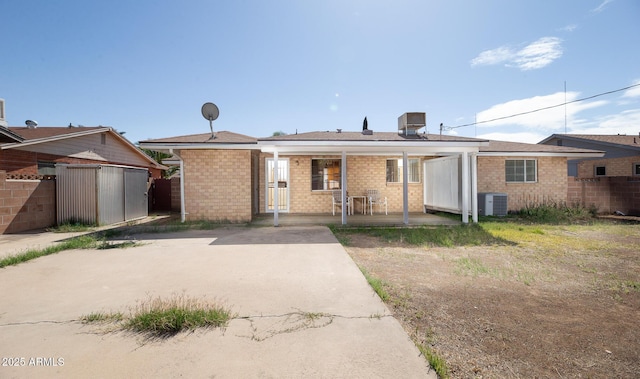 view of front of home with a porch, central air condition unit, and brick siding