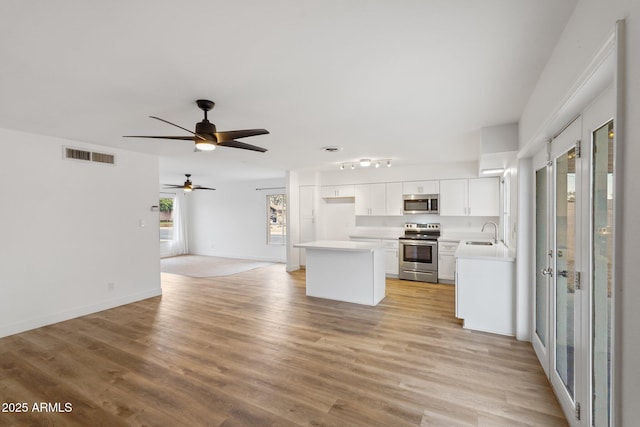 kitchen featuring white cabinetry, sink, ceiling fan, stainless steel appliances, and light hardwood / wood-style flooring