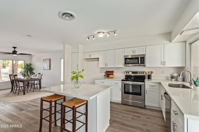 kitchen featuring sink, appliances with stainless steel finishes, white cabinetry, a center island, and dark hardwood / wood-style flooring