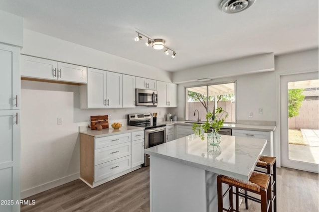 kitchen with a kitchen bar, a kitchen island, a wealth of natural light, stainless steel appliances, and white cabinets