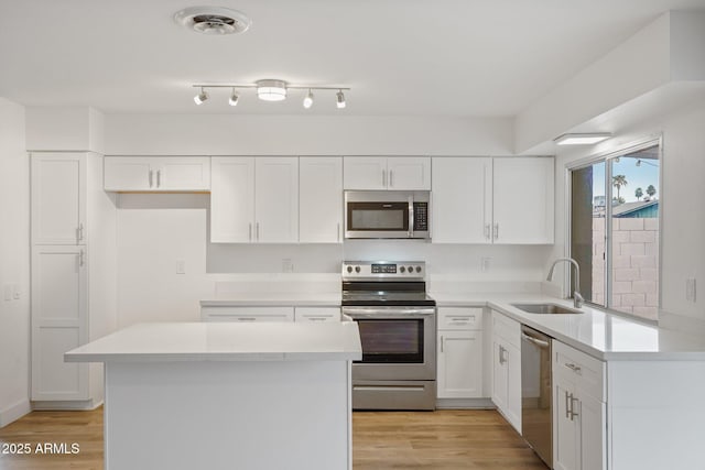 kitchen featuring stainless steel appliances, sink, white cabinets, and light hardwood / wood-style flooring