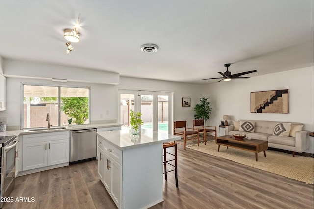 kitchen with sink, a breakfast bar area, white cabinetry, appliances with stainless steel finishes, and a kitchen island