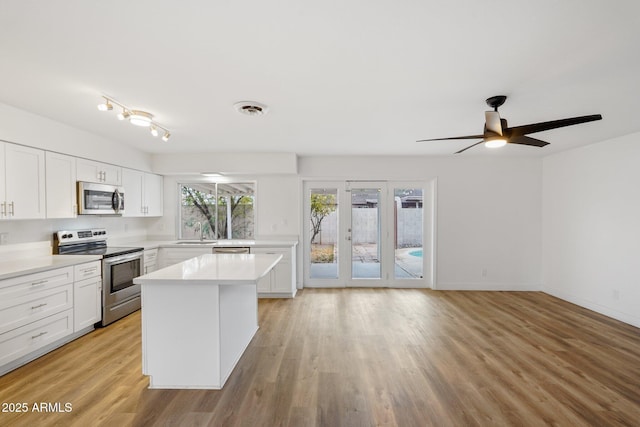 kitchen featuring sink, white cabinetry, light wood-type flooring, a kitchen island, and stainless steel appliances