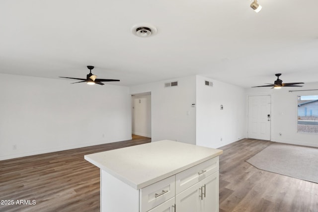 kitchen featuring a kitchen island, white cabinets, ceiling fan, and light hardwood / wood-style flooring