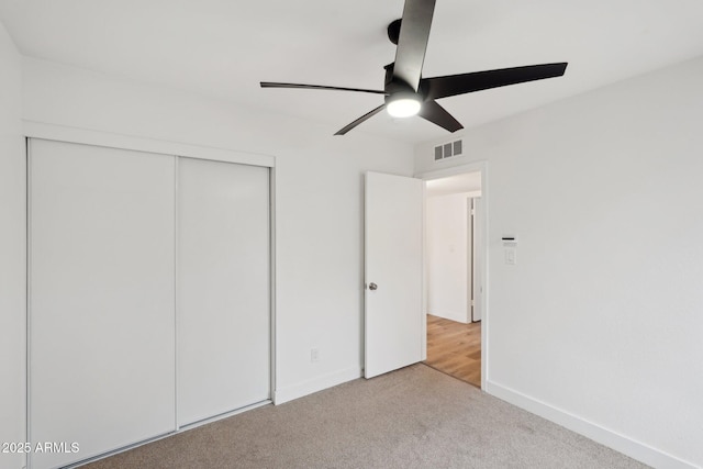 unfurnished bedroom with light colored carpet, ceiling fan, and a closet