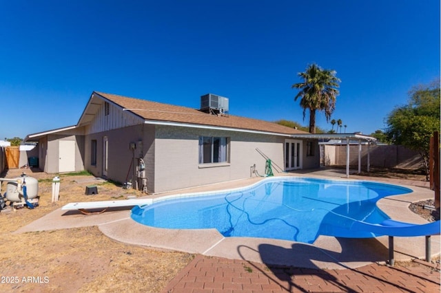 view of pool with a diving board and central air condition unit