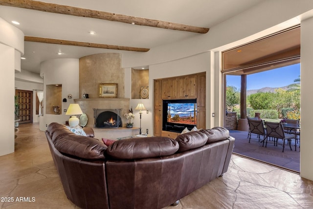 living area featuring beamed ceiling, recessed lighting, stone finish flooring, and a fireplace