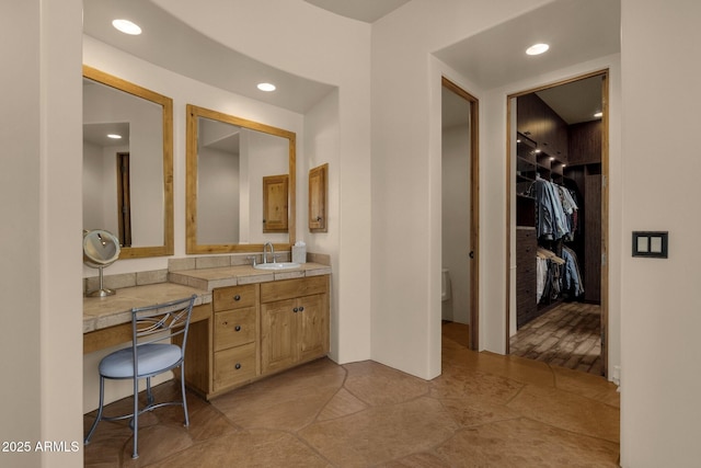 bathroom with toilet, recessed lighting, vanity, and a spacious closet