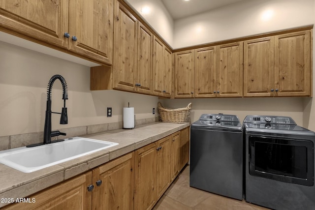washroom featuring a sink, cabinet space, and independent washer and dryer