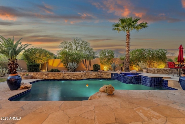 pool at dusk with a patio, a fenced in pool, a fenced backyard, and an in ground hot tub