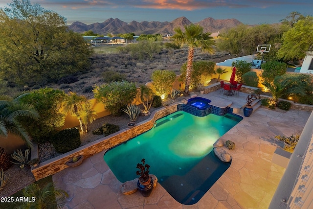 view of pool featuring a pool with connected hot tub, a patio, a mountain view, and a fenced backyard