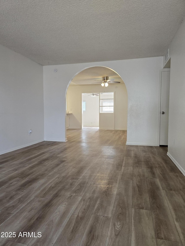 unfurnished room featuring dark wood-type flooring, ceiling fan, and a textured ceiling