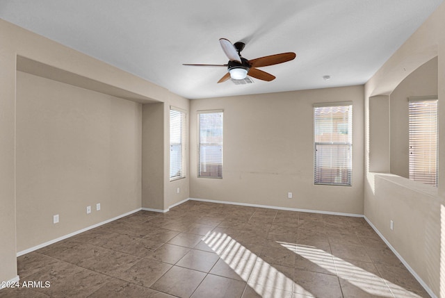 empty room featuring ceiling fan and a wealth of natural light