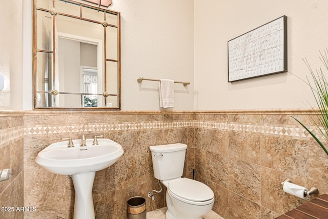 bathroom with toilet and tile walls