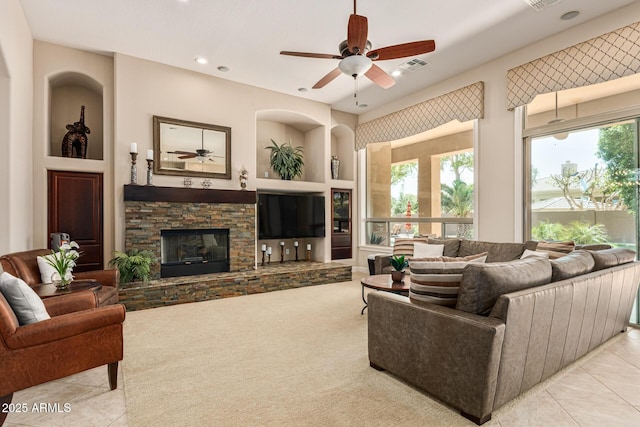 tiled living room with ceiling fan and a fireplace