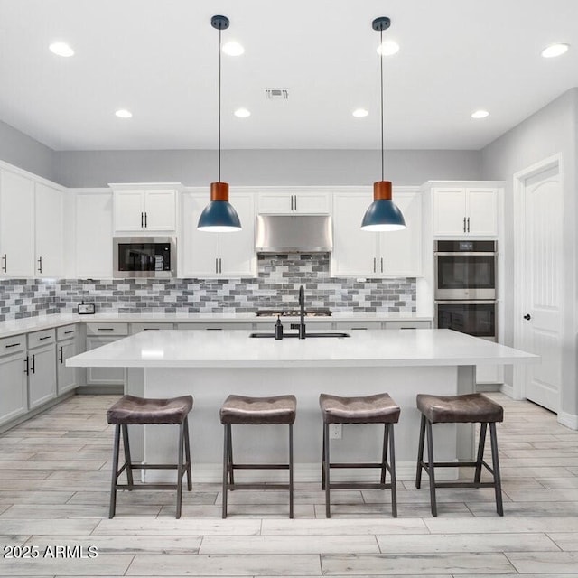 kitchen with under cabinet range hood, visible vents, appliances with stainless steel finishes, and light countertops