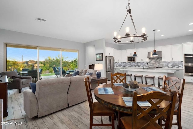 dining space with light wood-style floors, visible vents, a notable chandelier, and recessed lighting