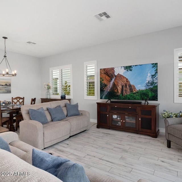 living area featuring light wood-type flooring, baseboards, visible vents, and a chandelier