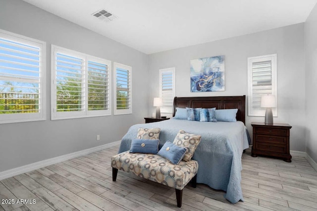 bedroom with baseboards, visible vents, and wood finished floors