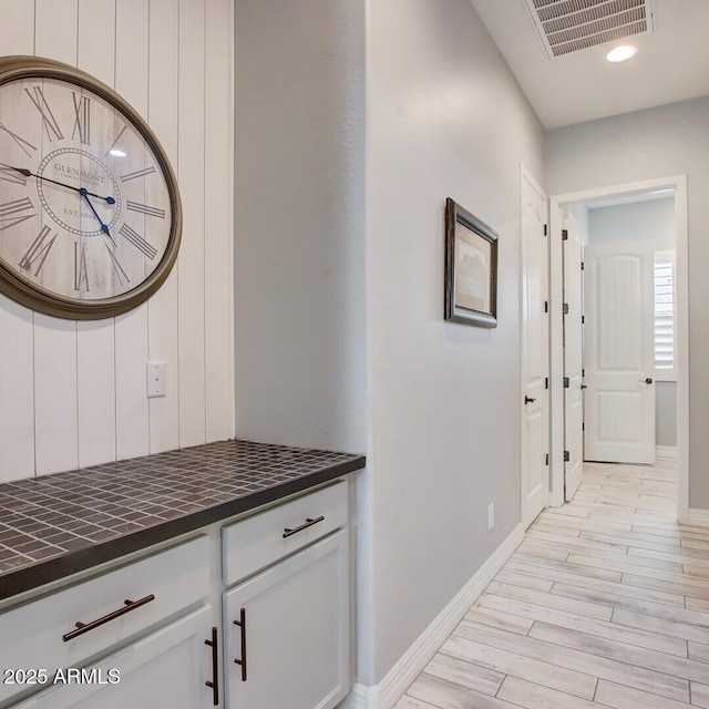 hallway featuring wood finish floors, visible vents, and baseboards