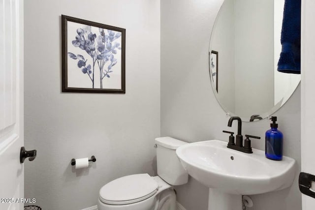 bathroom with toilet, baseboards, and a sink