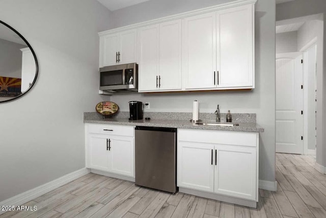 kitchen with light wood-style floors, white cabinetry, appliances with stainless steel finishes, and a sink