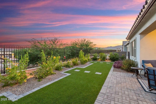 yard at dusk with a fenced backyard and a patio