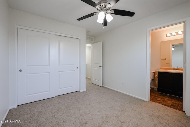 unfurnished bedroom featuring carpet, ensuite bathroom, sink, ceiling fan, and a closet