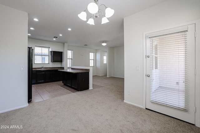 kitchen featuring pendant lighting, an inviting chandelier, light colored carpet, and a kitchen island