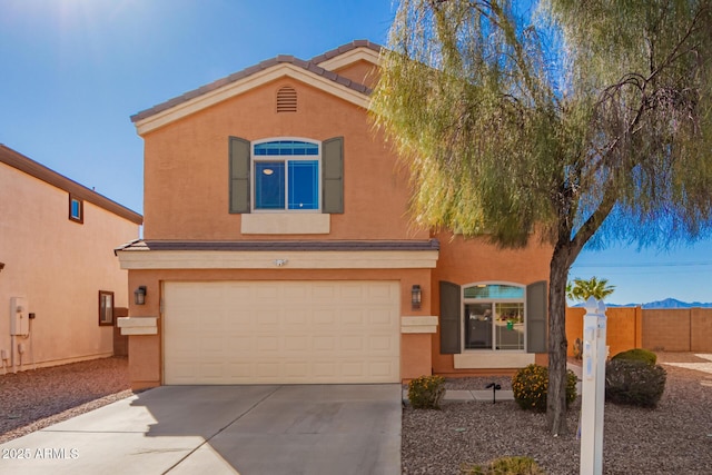 view of front of house featuring fence, a tile roof, concrete driveway, stucco siding, and a garage
