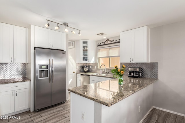 kitchen with wood finish floors, visible vents, a sink, stainless steel appliances, and stone counters