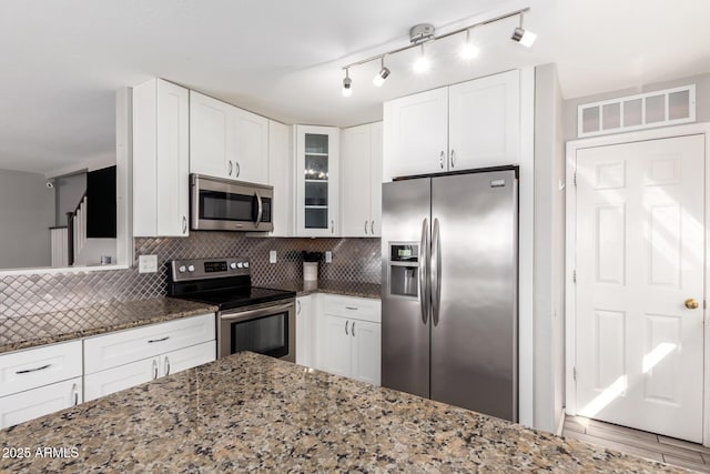 kitchen with visible vents, dark stone counters, decorative backsplash, stainless steel appliances, and white cabinetry