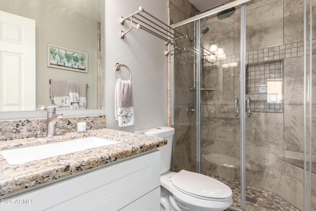 full bathroom featuring a stall shower, toilet, and vanity