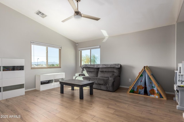 living room with visible vents, wood finished floors, baseboards, ceiling fan, and vaulted ceiling