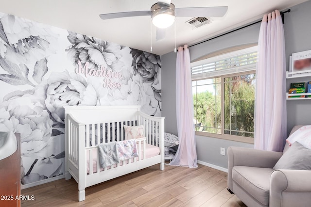 bedroom featuring a ceiling fan, wood finished floors, visible vents, and baseboards