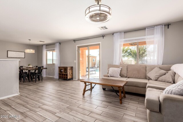 living room with visible vents, baseboards, and light wood finished floors