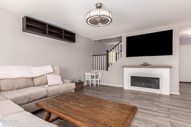living area with baseboards, a glass covered fireplace, and wood tiled floor