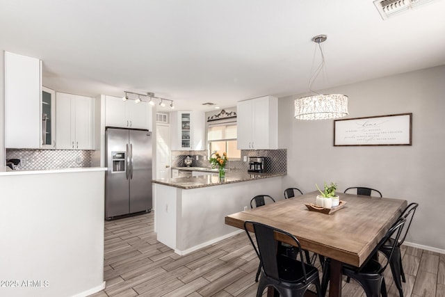 dining space featuring visible vents, baseboards, and wood tiled floor