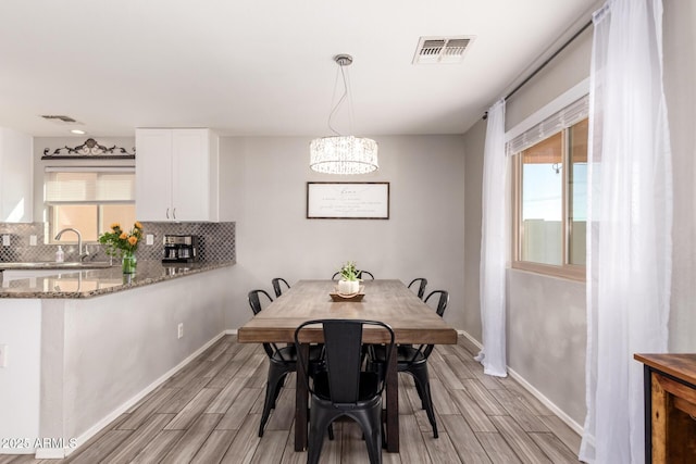 dining area with an inviting chandelier, baseboards, visible vents, and wood finish floors