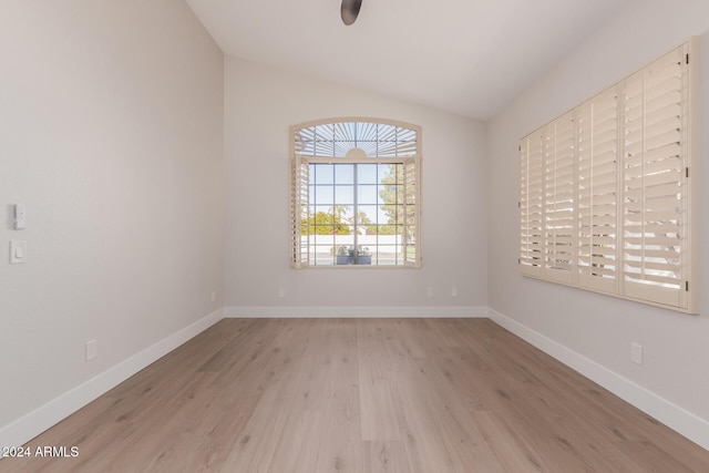 spare room featuring light wood-type flooring and vaulted ceiling