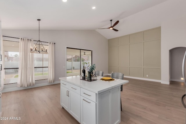 kitchen with a center island, white cabinets, vaulted ceiling, light hardwood / wood-style flooring, and decorative light fixtures