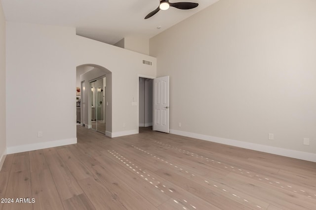 empty room with light hardwood / wood-style floors, high vaulted ceiling, and ceiling fan