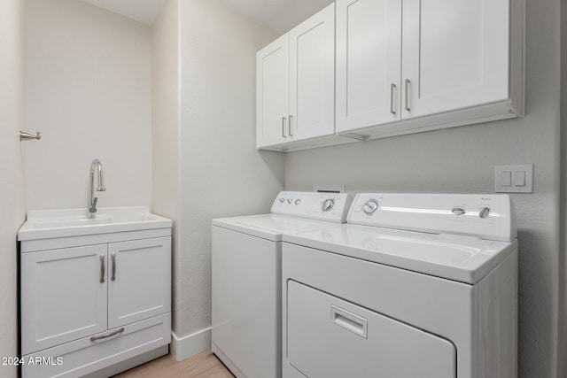 laundry room with cabinets, light hardwood / wood-style floors, washing machine and dryer, and sink