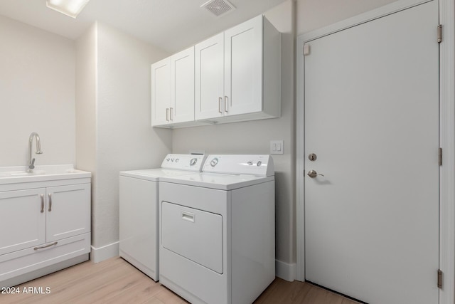 washroom with separate washer and dryer, cabinets, sink, and light hardwood / wood-style floors