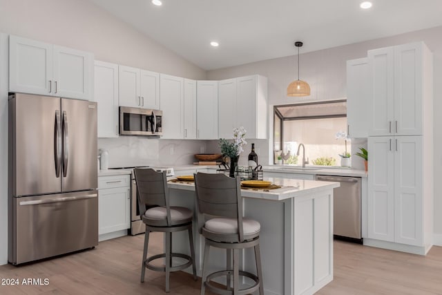 kitchen featuring white cabinets, light wood-type flooring, vaulted ceiling, and appliances with stainless steel finishes