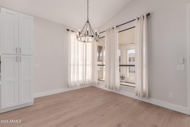 unfurnished dining area featuring a notable chandelier, lofted ceiling, and light hardwood / wood-style flooring