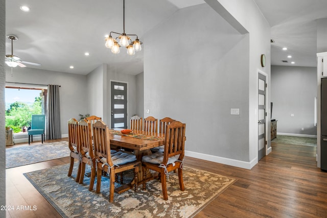 dining room featuring ceiling fan with notable chandelier, vaulted ceiling, and dark hardwood / wood-style flooring