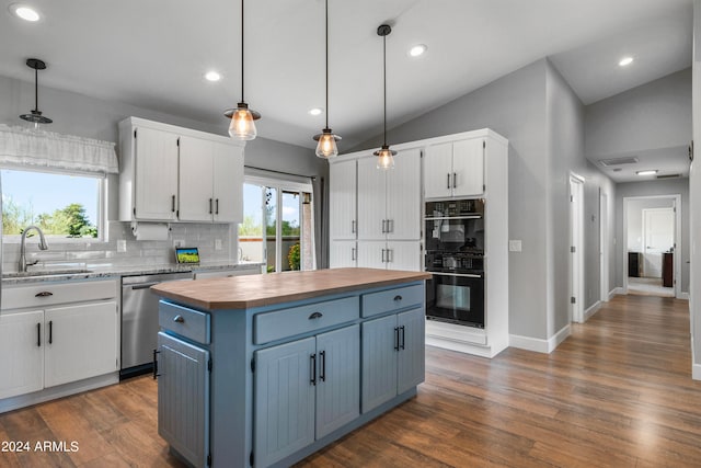 kitchen with white cabinetry, lofted ceiling, a kitchen island, and decorative light fixtures