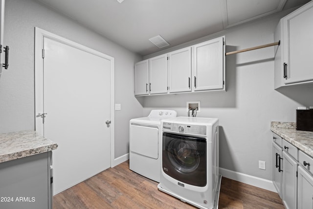 laundry area with cabinets, washing machine and clothes dryer, and hardwood / wood-style floors